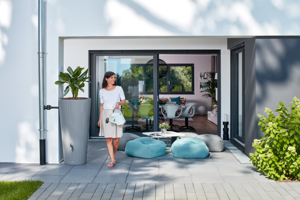 Person mit Gießkanne auf Terrasse